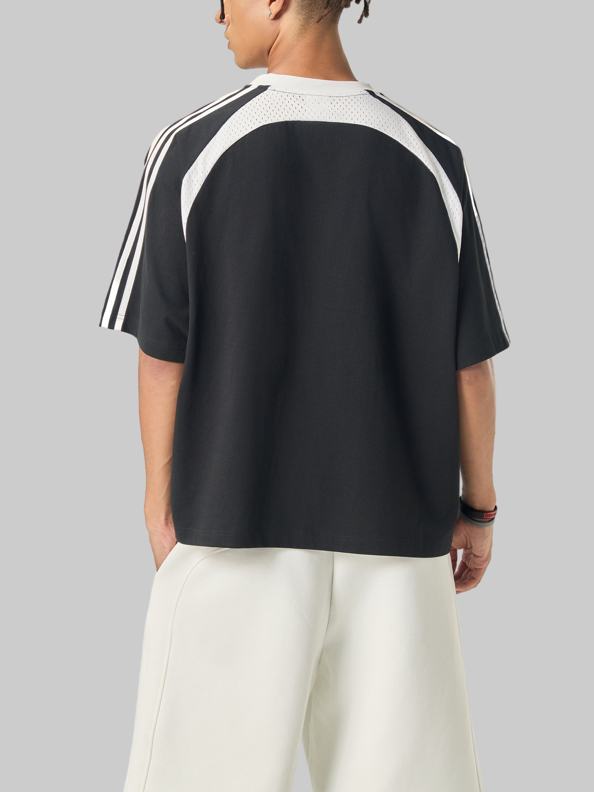 Person wearing a black and white Adidas t-shirt on a white background