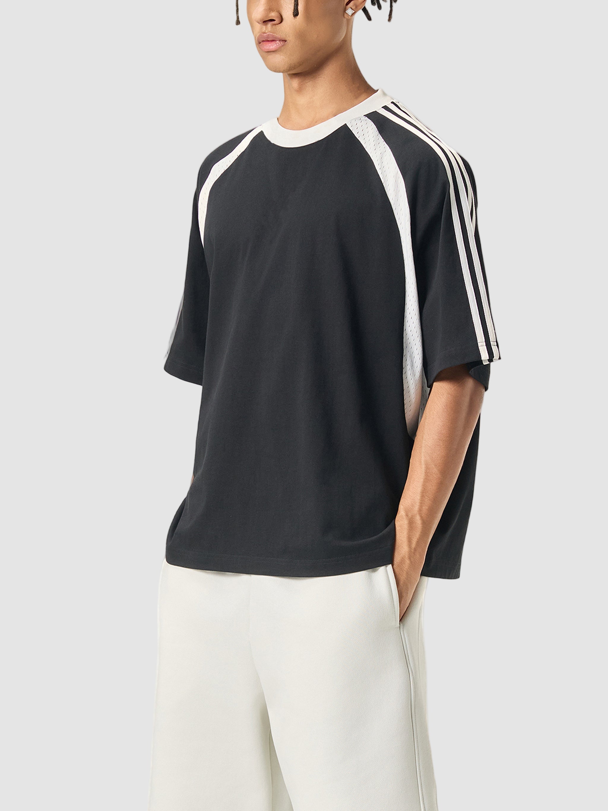 Person wearing a black and white Adidas t-shirt on a white background