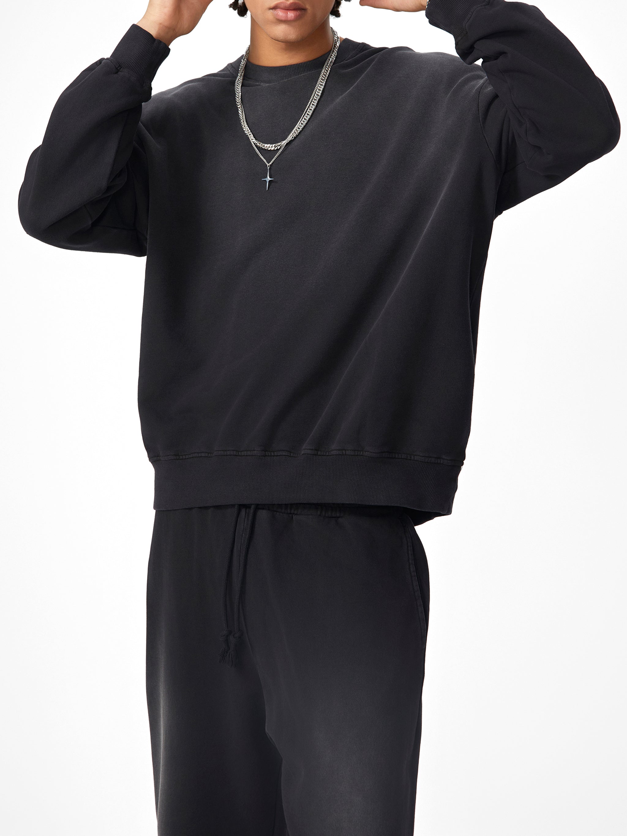Person wearing a black sweatshirt and pants on a white background