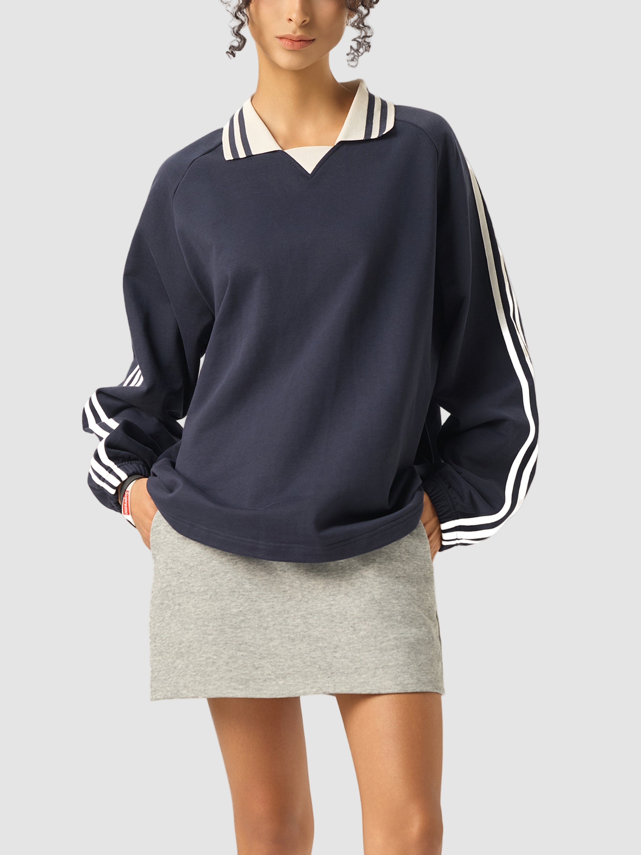 Navy sweatshirt with white stripes on sleeves and collar worn by a person on a white background