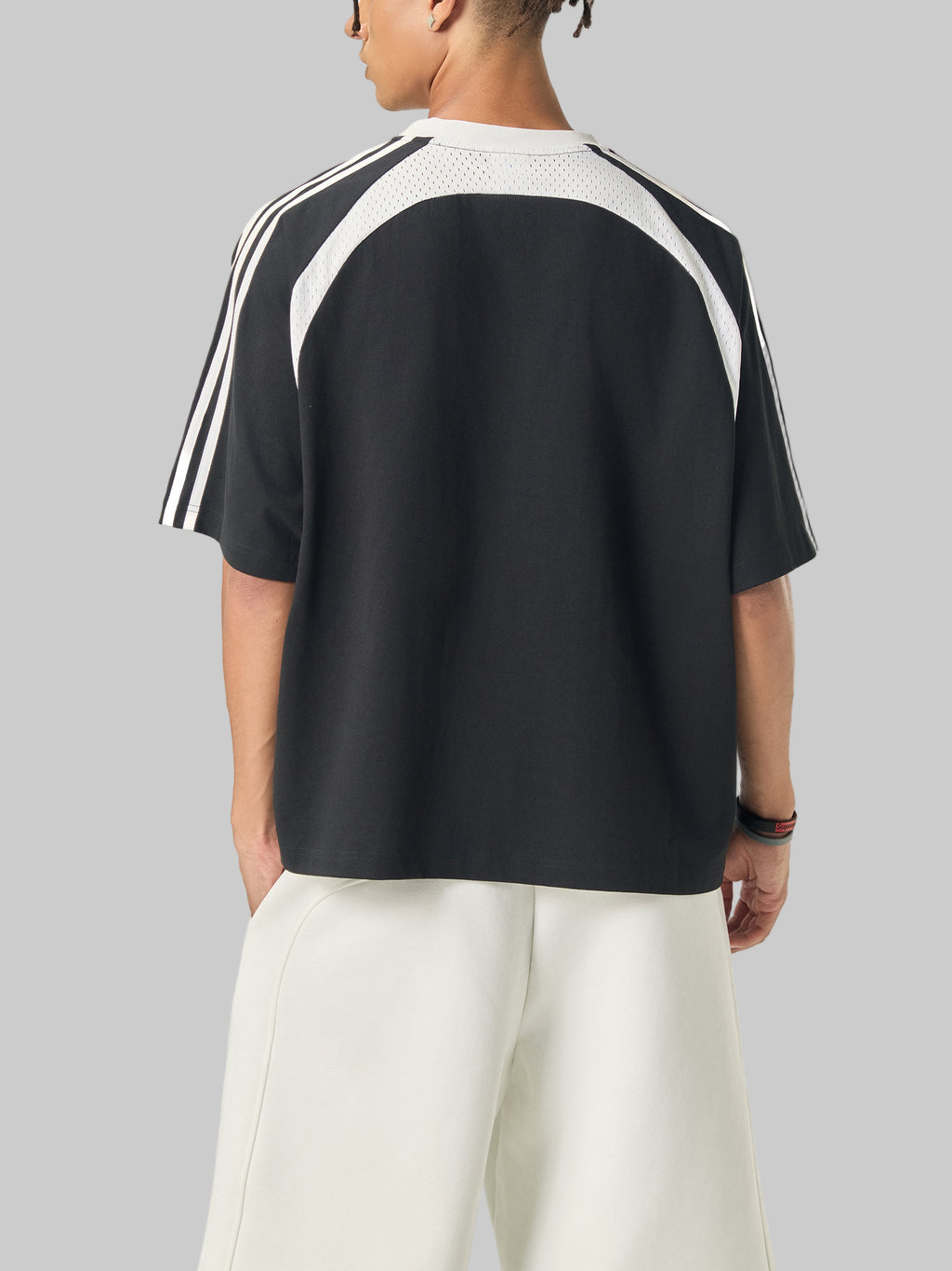 Person wearing a black and white Adidas t-shirt on a white background