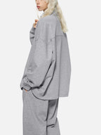 Person wearing a gray oversized sweater and pants on a white background