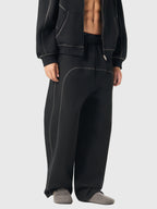 Person wearing black tracksuit pants and jacket on a white background