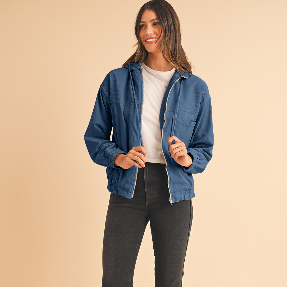 Woman wearing a blue denim jacket and black jeans on a beige background